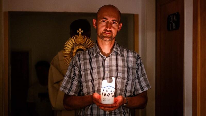 Jedna nesoucí svíčku před nejsvětší v monstranci.